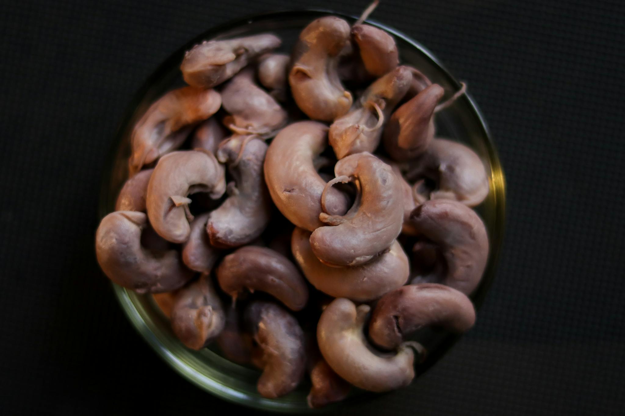 Top view of raw cashew nuts piled in a bowl, perfect for food and ingredient themes.